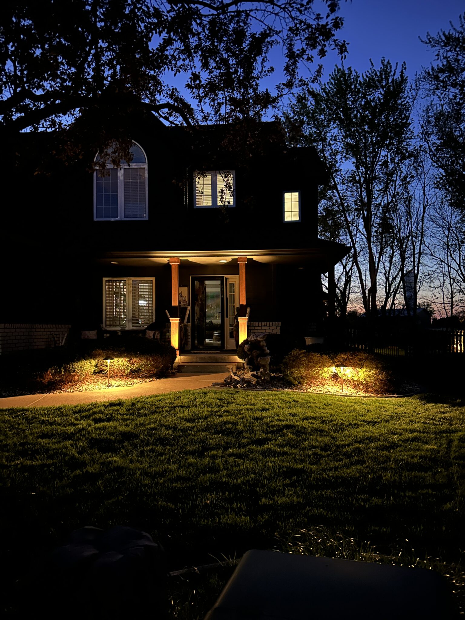 Landscape lighting highlighting front yard of home at night