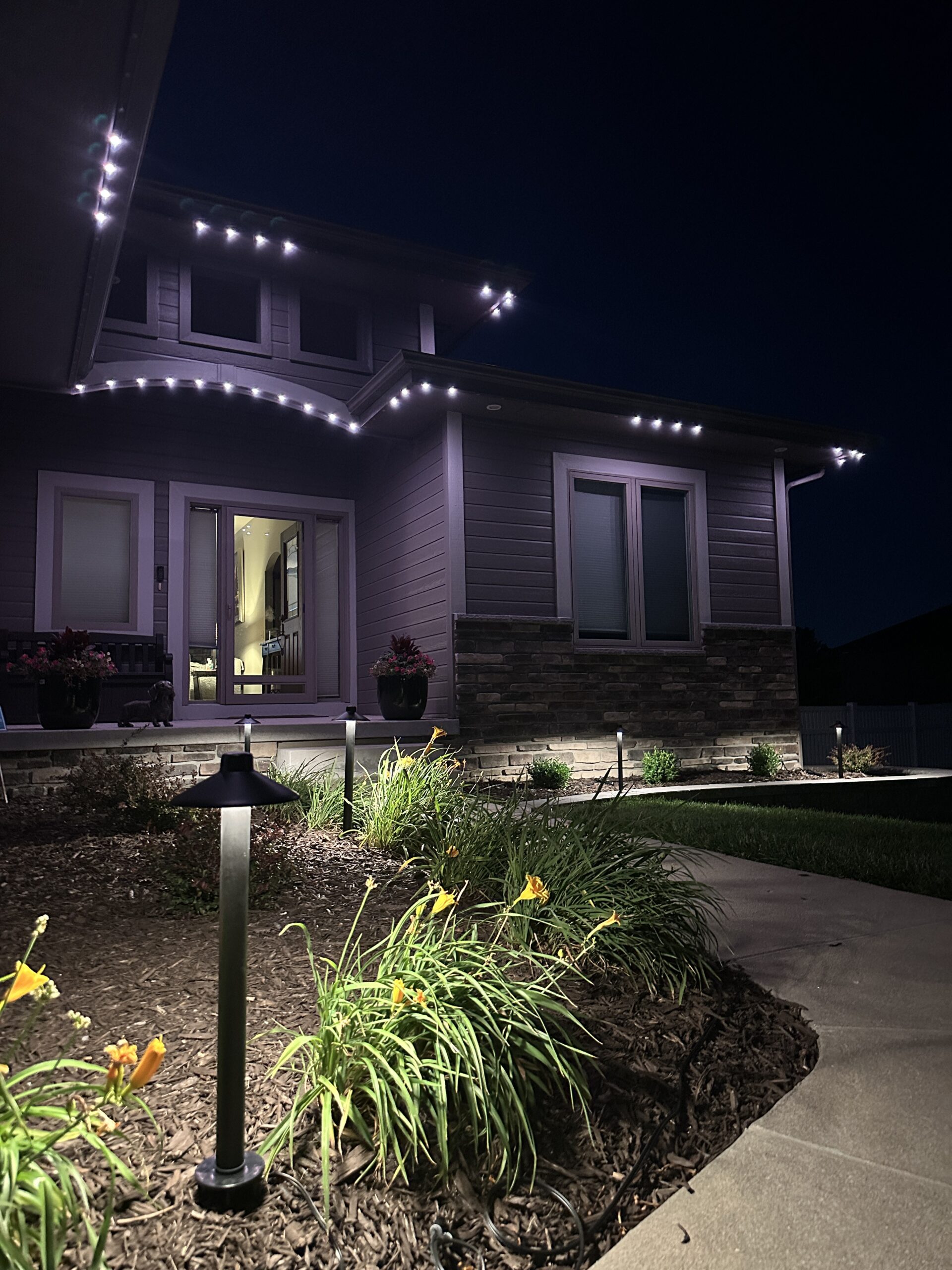 Landscape pathway lighting and permanent roofline lights on residential home